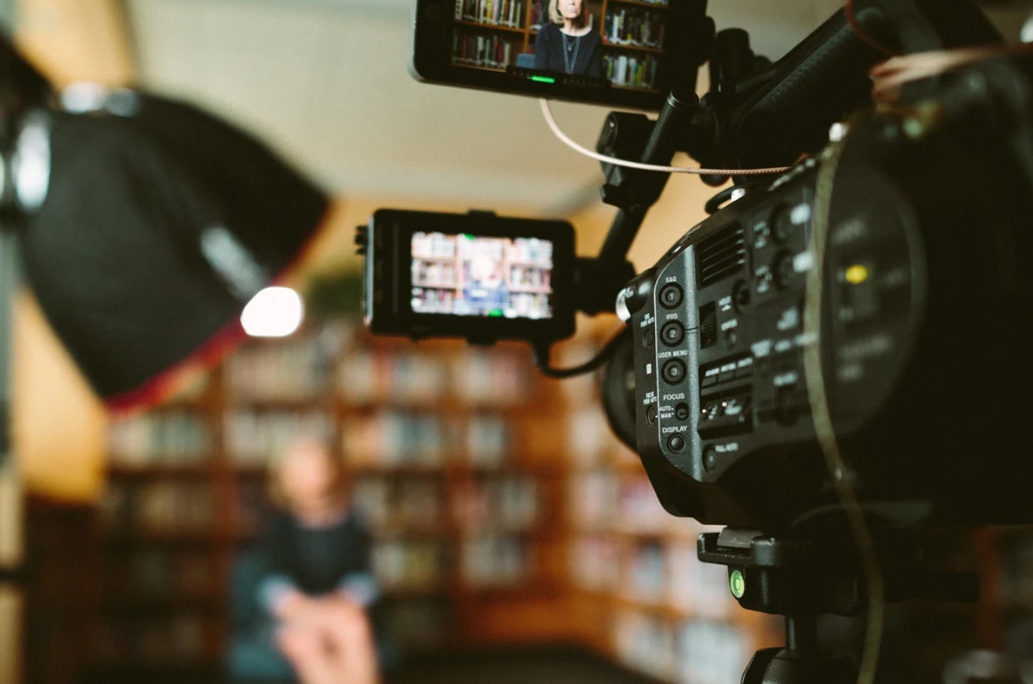 Professional video production setup capturing an interview in a library setting, with focus on camera equipment and lighting – ideal for scientific or corporate video marketing.